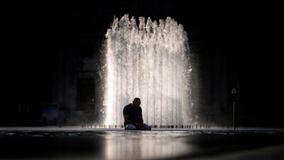 A man sits at the Louvre pyramid in Paris as a heat wave hits the French capital. AFP