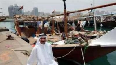 Darkish Rashid Lootah, a veteran Abu Dhabi fisherman, sits among boats tied up at Mina.
