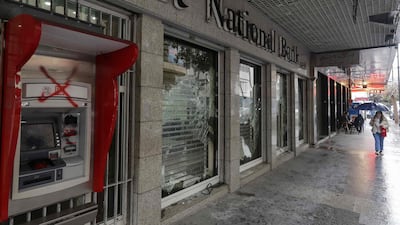 A woman walks past a bank, with windows damaged by anti-government protesters, in the capital Beirut. Debt-ridden Lebanon is facing its most serious economic crisis since the end of the 1975-1990 civil war. AFP