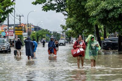 People wade through a flooded street after heavy rain in Badung, Bali. Reuters