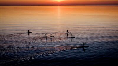 Paddle boarders tour the calm Baltic Sea in Timmendorfer Strand, northern Germany, as the sun rises on a cold spring morning. AP