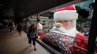 People walk past a large inflatable Santa Claus outside a shopping mall in Bangkok, Thailand. EPA