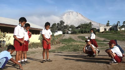 Students play before the start of their class as Mount Sinabung is seen in the background, at an elementary school in Beganding, North Sumatra. Ahmad Putra / AP Photo