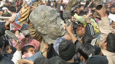 Iraqi Shiite men beat a bust of ousted president Saddam Hussein in Baghdad in 2003. Ahmad Al Rubaye / AFP