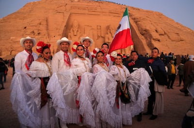Men and women dressed in traditional Mexican clothing pose with a Mexican flag as visitors gather outside Ramses II's Great Temple in Abu Simbel. AFP