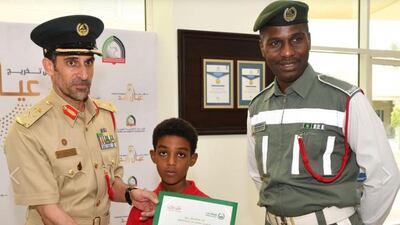 Mustafa Awad Yehia, right, with his young son, centre, was promoted following the incident. Dubai Police