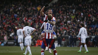 Atletico's Mario Mandzukic, top, celebrates his goal with teammate Fernando Torres, bottom, during their La Liga win against Real Madrid on Saturday. Andres Kudacki / AP