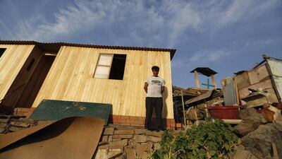 Roberto Taboada at his new house (left), next to the old one (right), in Gosen City. Taboada has lived for years in Gosen but recently saved enough from working odd jobs as a handyman to build a solid home. Mariana Bazo / Reuters