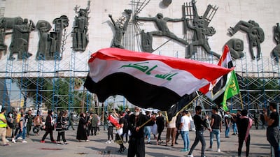 A protester waves a large Iraqi flag in Tahrir Square during a demonstration calling for the government to resign, in Baghdad, Iraq on November 15, 2020. AP