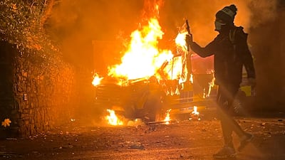 A protester films and a police vehicle burns during a demonstration outside a hotel housing asylum seekers in Saggart, Co Dublin. Police in riot gear clashed with about 500 protesters in the Irish capital outside an asylum seeker hotel following allegations that a 10-year-old girl was sexually assaulted. AFP