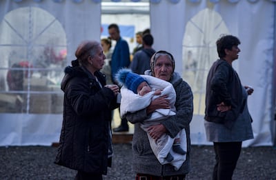 An elderly woman holding an infant waits as ethnic Armenians from Nagorno-Karabakh arrive at a registration centre near the border town of Kornidzor, Armenia. EPA