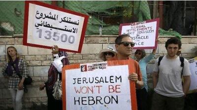 Foreign and Israeli left-wing activists hold posters during a weekly protest to show solidarity with Palestinians against a Jewish settlement in the Sheikh Jarrah neighbourhood in East Jerusalem July 8, 2011.