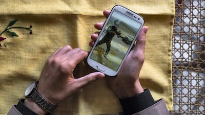 Amir displays a photo of himself in his battle fatigues, during his training in Iran in 2015. Kern Hendricks / The National.