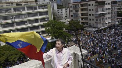 A person waves a Venezuelan flag as demonstrators gather during an anti-government protest in Caracas, Venezuela. Bloomberg