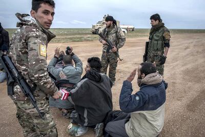 Men suspected of belonging to ISIS are screened by members of the Syrian Democratic Forces after fleeing from the last pocket of territory held by the group outside Baghouz. Campbell MacDiarmid / The National