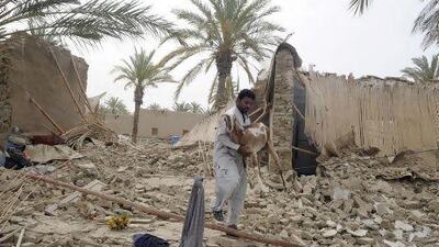 A Pakistani earthquake survivor carries a goat among the rubble of collapsed mud houses in the Mashkail area of the southwestern Baluchistan province.
