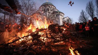People gather for the annual bonfire outside the Saint Sava church during the ceremonial burning of dried oak branches, symbolising the Yule log during the Orthodox Christmas eve celebrations in Belgrade, AFP
