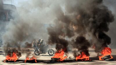People ride a motorcycle past burning tires during protests against the deteriorating economic situation and the devaluation of the local currency, in Taiz, Yemen, on September 27, 2021. Reuters.