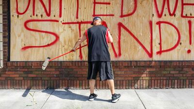 Tom Bernard, cleans the front of his damaged shop on June 1, 2020 in Minneapolis, Minnesota, after protests for George Floyd, an unarmed black man who died after being pinned to the ground by a Minneapolis police officer in Minneapolis, Minnesota. AFP