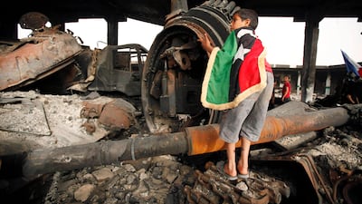 A Libyan boy climbs up the remains of a tank belonging to forces loyal to Muammar Gaddafi at a vegetable market near Tripoli street, in central Misrata in this May 22, 2011 file photo. When Gaddafi's government shut off the cellphone network in Misrata in the early days of Libya's uprising, it wanted to stop rebel forces communicating with each other. But the power of a modern phone goes beyond its network. Both rebels and government soldiers have used their phones to take pictures and videos of the conflict, a digital record of fighting from both sides. With the rebels now in Tripoli, the capital, and Gaddafi's whereabouts unknown, those gigabytes of potential evidence may play a role in any war crimes cases. Picture taken May 22, 2011. To match Special Report LIBYA-MISRATA/ REUTERS/Zohra Bensemra/Files (LIBYA - Tags: POLITICS CIVIL UNREST SCI TECH BUSINESS) *** Local Caption *** ZOH28_LIBYA-MISRATA_0823_11.JPG