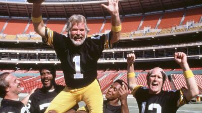 Kenny Rogers suits up with the Pittsburgh Steelers, for the singers third CBS television special, "Kenny Rogers America." (also known as Kenny Rogers: Working America.) Originally broadcast Thursday, November 20, 1980. Steelers football players with Kenny. Left to right: Rocky Bleier (20); Mean Joe Greene (75); Kenny Rogers (1); Lynn Swann (88); and Terry Bradshaw (12). Getty Images)