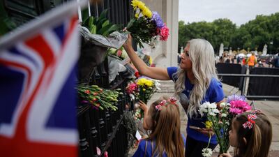 A family leaves flowers outside Buckingham Palace. EPA