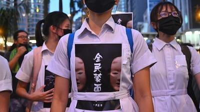 High school students chant slogans as they stick posters reading "all people masked" on their uniforms after the government announced a ban on facemasks. AFP