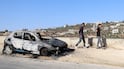 People walk past a damaged car after an attack by Israeli settlers in the village of Jalud in the West Bank. EPA