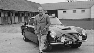 English entrepreneur David Brown, owner of Aston Martin Lagonda, posing with an Aston Martin DB6 in 1966