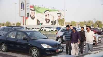 A group of men walks at a pedestrian crossing, gesturing to a driver to wait, near Marina Mall. Silvia Razgova / The National