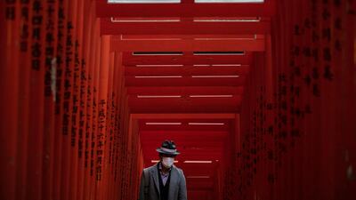A man with a mask walk through torii gates at the Hie Shrine In Tokyo. The coronavirus has claimed its first victim in the United States as the number of cases shot up in Iran, Italy and South Korea and the spreading outbreak shook the global economy. AP