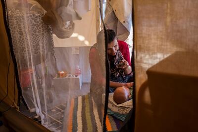 A young Afghan asylum seeker, a new mother, cares for her baby, who was born a few months after she and her husband arrived at the Oinofyta camp on the outskirts of Athens, Greece. Fahrinisa Campana for The National