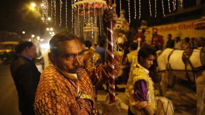 A member of Indian Brass band, holds decorative lights as he accompanies a wedding procession, in New Delhi,