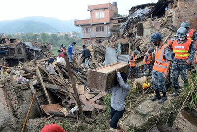 People carry belongings amid the rubble of collapsed houses in Bhaktapur on the outskirts of Kathmandu on April 27, 2015, two days after a 7.8 magnitude earthquake. AFP Photo