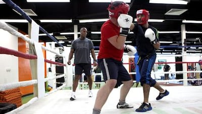 The boxing coach Ricky Miller, back, watches Jaafar Al Aidaroos, front, and Adam Buck preparing for the big Friday fight, the grand finale of the Corporate Contender white-collar boxing programme. Fatima Al Fatima Al Marzooqi / The National