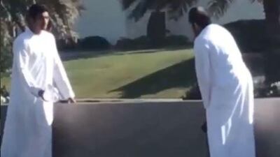 A screenshot from the Instagram post of Abu Dhabi Network that shows two men assisting a stray cat.