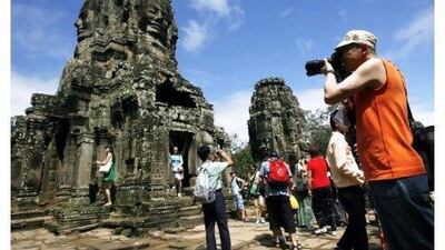 Tourists take photographs during a tour of the Bayon Temple, part of the Angkor temple complex.