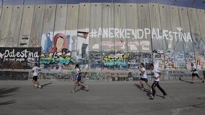 Participants run past Israel's West Bank separation barrier during the Palestine Marathon in Bethlehem. Ammar Awad / Reuters