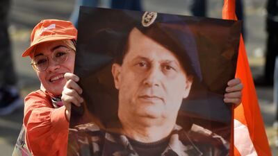 A supporter of the outgoing Lebanese President Michel Aoun holds his portrait during a gathering at Baabda Palace. Mr Aoun served in the Lebanese Army from 1958 to 1991. EPA