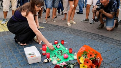 A woman lights a candle next to flowers and messages to the victims. Javier Soriano / AFP Photo