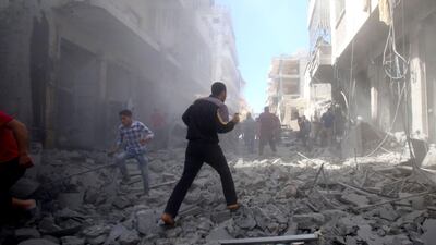 Survivors of an airstrike from regime forces on Maaret Al Noman, Idlib, walk through debris. Abd El Aziz Qitaz / AFP