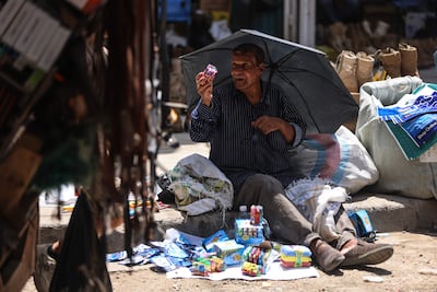 A man shields himself from the sun as he sells lighters at a market in central Baghdad. Many Iraqis are in the grip of economic hardship. AFP
