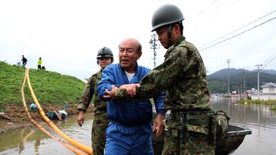 Japanese troops guide a man from a flooded area during search and rescue operations in the aftermath of Typhoon Hagibis in Marumori, Miyagi prefecture. AFP