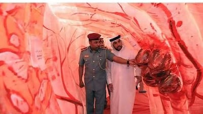 Ayman Kamel Ibrahim, the security officer of Health Authority-Abu Dhabi, right and Sami Zayed al Monzeui, a police officer, walk through a giant replica of a human colon that has been installed at the health authority's headquarters.