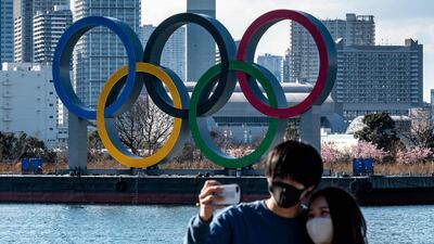 A couple pose for photos in front of the Olympic rings on display at the Odaiba waterfront in Tokyo on February 24, 2021. AFP
