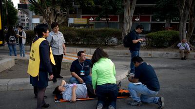 A woman is helped outside, along Reforma Avenue after a 7.2-magnitude earthquake shook Mexico City. Eduardo Verdugo / AP Photo