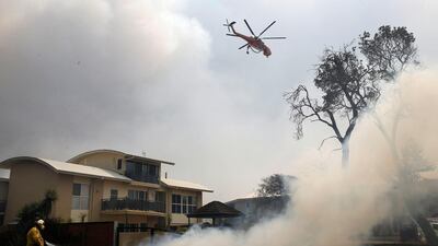 A fire bombing helicopter works to contain a bushfire along Old Bar road in Old Bar, New South Wales, Australia. REUTERS