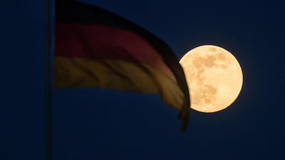 The supermoon illuminates a German national flag flying in Berlin. Bloomberg