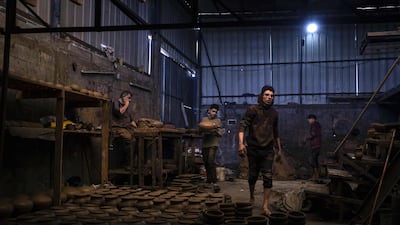 Palestinian potter Sid Atallah, left, and his sons at work at the family workshop in Deir al-Balah in the central Gaza Strip. AFP