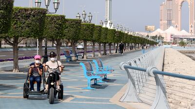 Residents ride e-scooters along the Corniche in Abu Dhabi. Khushnum Bhandari / The National
